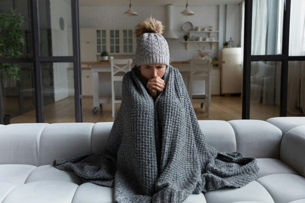 woman cold in home because furnace is blowing cold air