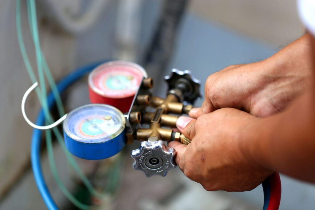 Technician using manifold gauges to check refrigerant pressure on an air conditioner