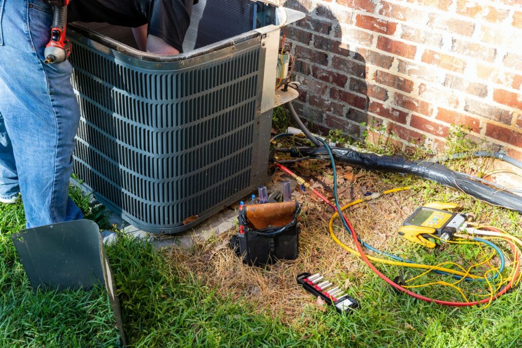 HVAC technician performing a diagnostic check on an outdoor air conditioner that is running but not cooling