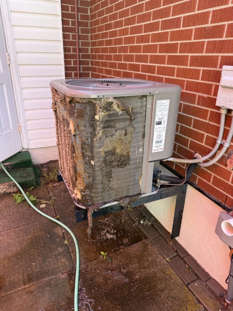 Condenser coil of a two-year-old Lennox air conditioner packed with cottonwood fluff and yard debris before AC maintenance at a Waterloo rental property