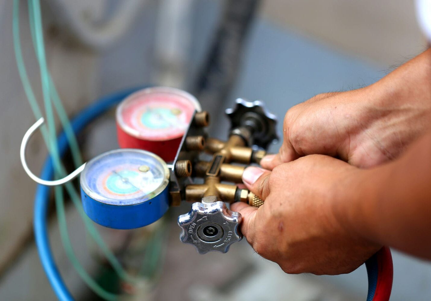 Technician using manifold gauges to check refrigerant pressure on an air conditioner