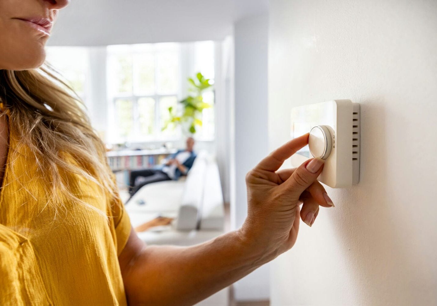 woman adjusting ac thermostat