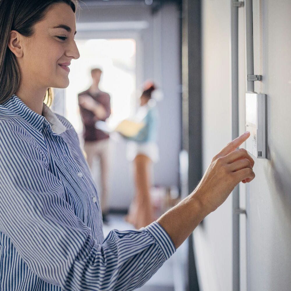 woman adjusting her hvac thermostat woman adjusting her hvac thermostat